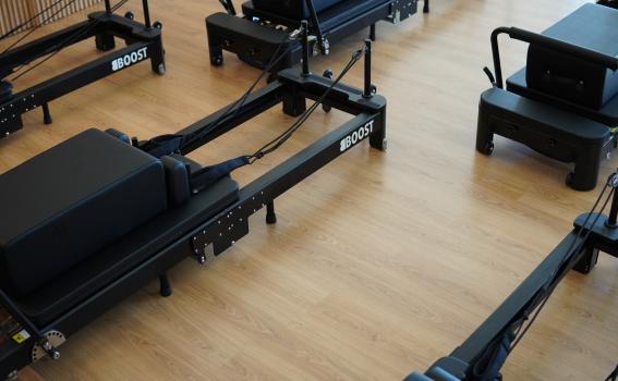 Vue surélevée de plusieurs machines de Pilates Reformer Boost noires, alignées les unes à côté des autres sur un sol en bois clair.