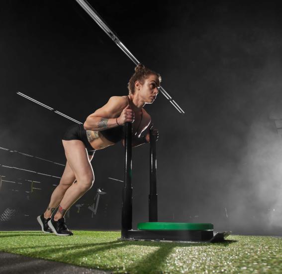 Sportive réalisant un exercice de poussée de traîneau pour un entraînement HYROX